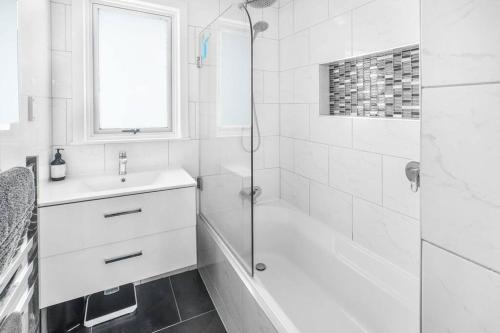 uma casa de banho branca com um chuveiro e um lavatório. em Home away from home! em Hamilton