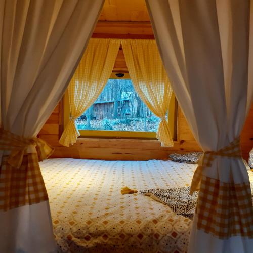 Schlafzimmer mit einem Fenster mit Vorhängen auf einem Bett in der Unterkunft Roulotte avec piscine la jonquille in Valgorge