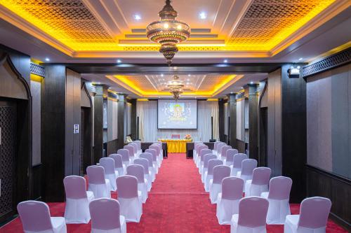 - une rangée de chaises blanches dans une pièce avec une scène dans l'établissement Amman Unique Hotel - SHA Plus, à Udon Thani