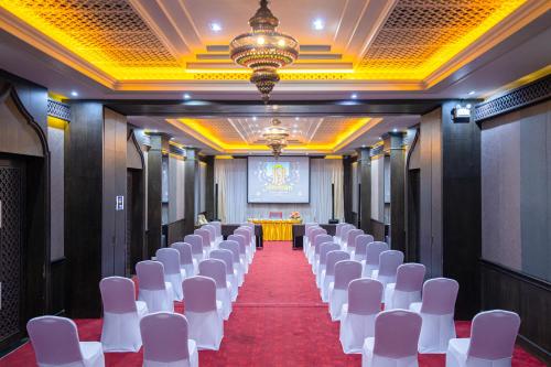 a row of white chairs in a room with a stage at Amman Unique Hotel in Udon Thani
