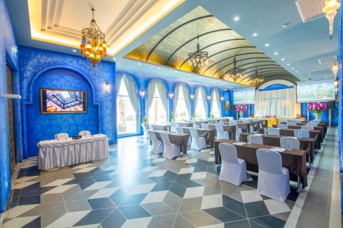 Amman Unique Hotel - SHA Plus في أودون ثاني: غرفة بجدران زرقاء وطاولات وكراسي بيضاء