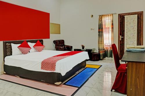 a bedroom with a large bed with a red wall at OYO 92405 Evergreen Hotel & Resto 