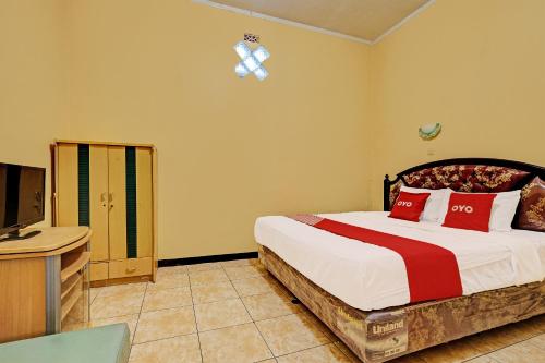 1 dormitorio con 1 cama grande y TV en OYO 92406 Hotel Renata 1, en Kopeng