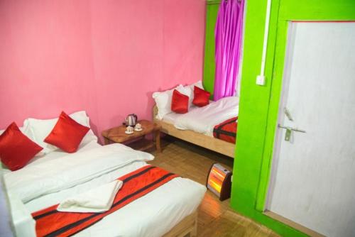 2 Betten in einem Zimmer mit rosa und grünen Wänden in der Unterkunft Hill Home Stay, Baichung in Nātang