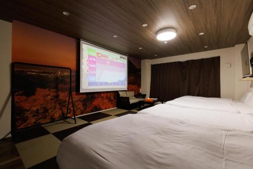 大阪市にあるカーサコモダ難波のベッドとプロジェクションスクリーン付きのホテルルーム