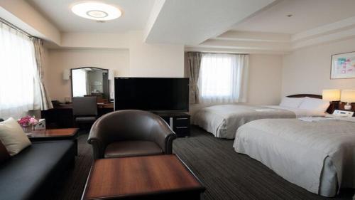 盛岡的住宿－HOTEL BRIGHT INN MORIOKA，酒店客房,设有两张床和一张沙发