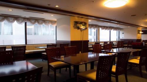 a dining room with tables and chairs and windows at HOTEL BRIGHT INN MORIOKA in Morioka