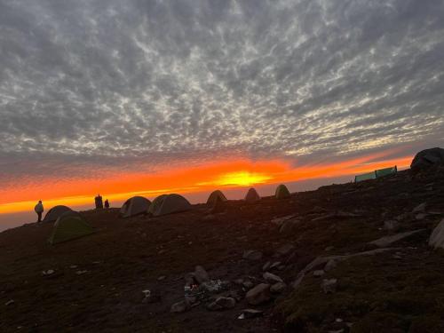 a group of people standing next to tents at sunset at Triund Trek and Camping in Dharamshala