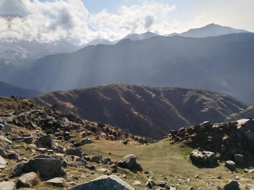 a group of rocks on a mountain with mountains in the background at Triund Trek and Camping in Dharamshala