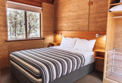 a bedroom with a bed and a window at Bussells Bushland Cottages in Margaret River Town
