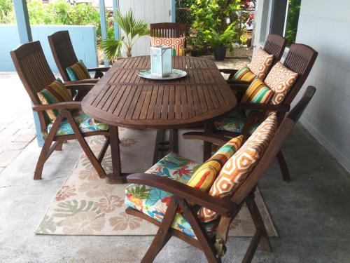 a wooden table with four chairs and a table with a candle at Hale Kai Ewa in Ewa Beach