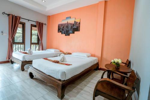 two beds in a room with orange walls at Kasalong Resort and Spa Pattaya in Pattaya Central