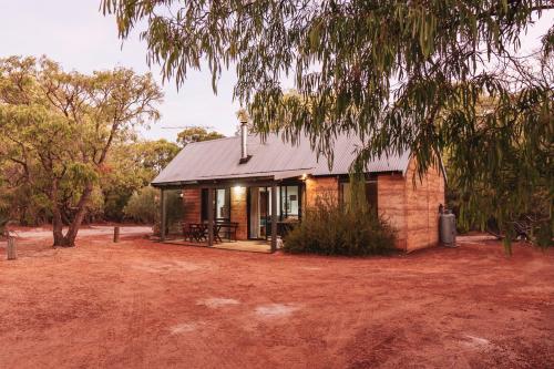 a small brick house in the middle of a yard at Bussells Bushland Cottages in Margaret River Town