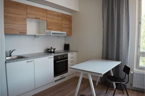 a small kitchen with white cabinets and a table at Soihtu Stay in Jyväskylä