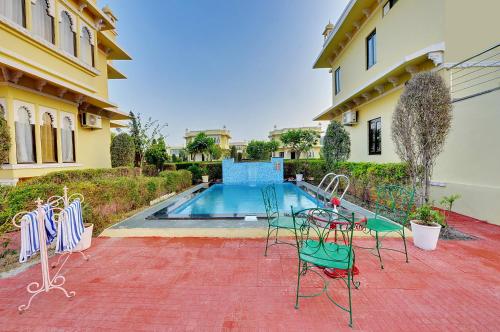 a pool with tables and chairs next to a house at Padmini Bagh Resort by Inventree, Udaipur in Udaipur