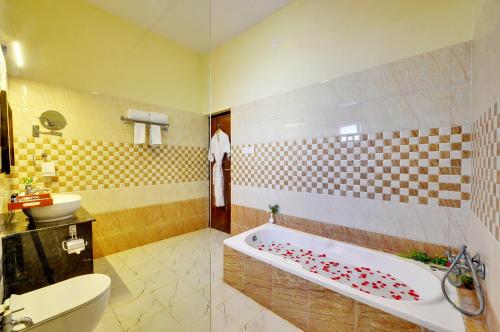 a bathroom with a tub and a toilet and a sink at Padmini Bagh Resort by Inventree, Udaipur in Udaipur