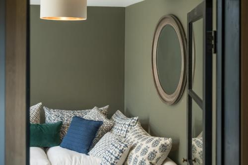 a room with pillows on a couch with a mirror at Designer Cotswold post house with external sauna in Tetbury