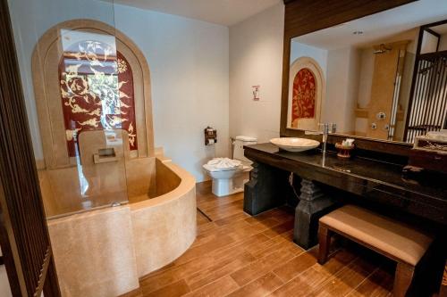 a bathroom with a tub and a toilet and a sink at Kasalong Resort and Spa Pattaya in Pattaya Central
