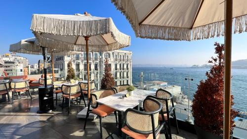ein Restaurant mit Tischen und Stühlen und Blick auf das Wasser in der Unterkunft The Wings Hotel Istanbul in Istanbul