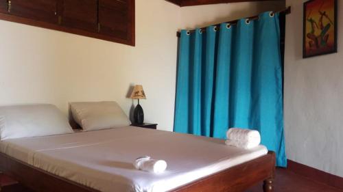 a bedroom with a bed with a blue curtain at WINGS HOTELS in Nosy Be