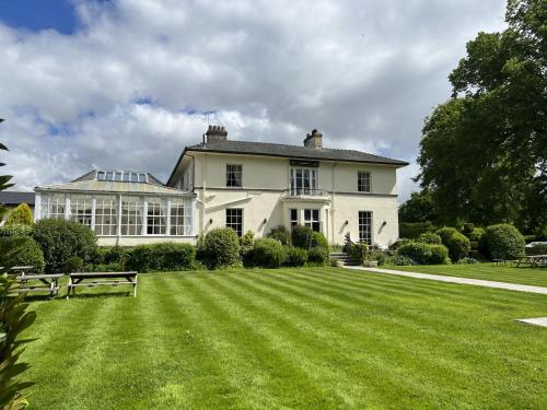 a large white house with a large lawn at Highfield Hall in Mold