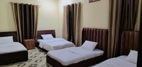 um quarto de hotel com duas camas e cortinas em AlZaeem Resort & Hotels em Barka