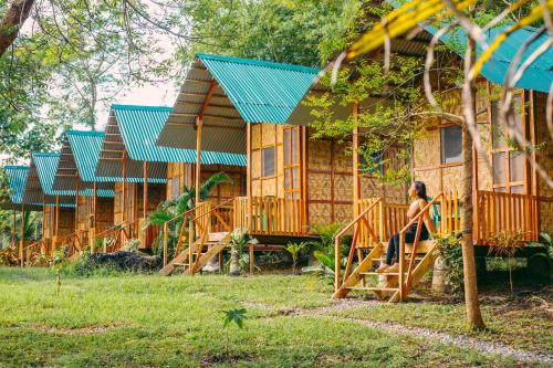 a row of wooden cabins with a woman sitting on the stairs in front at Green Acres Village in Moalboal