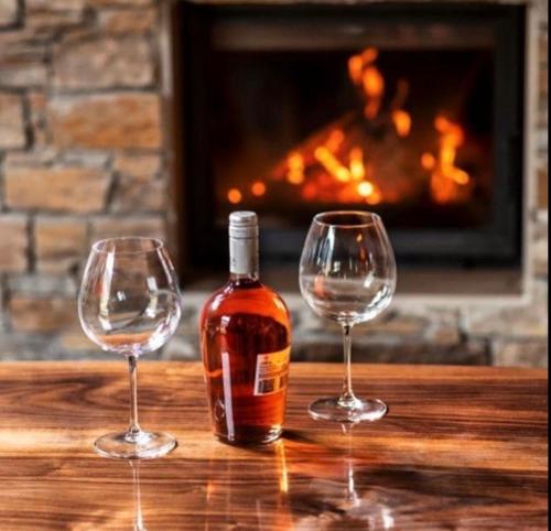 two wine glasses and a bottle of whiskey on a table with a fireplace at Luxus Spa auf tollem Anwesen in Neubulach