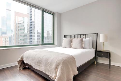 a white bedroom with a bed with a large window at Streeterville Studio w Pool Dog Run nr Beach CHI-582 in Chicago