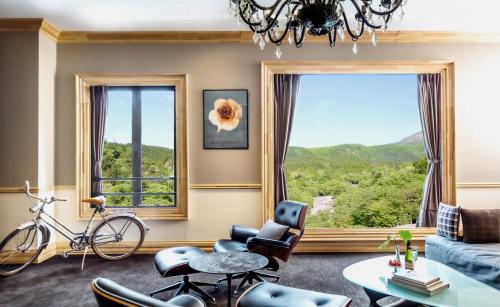 a living room with a couch and chairs and a large window at Shelter Garden Nikko in Nikko