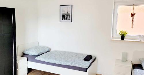 Bett in einem weißen Zimmer mit Fenster in der Unterkunft Modern Apartment Bedburg-Hau in Hau