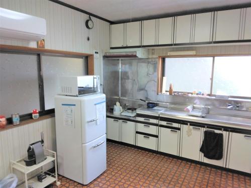 La cuisine est équipée d'un réfrigérateur blanc et d'un évier. dans l'établissement ゲストハウスみちしお, 