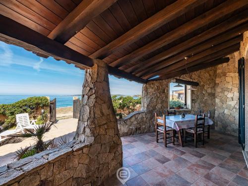 zewnętrzny widok na kamienny dom ze stołem i ocean w obiekcie Seafront Rustic Hideaway w mieście San Vero Milis