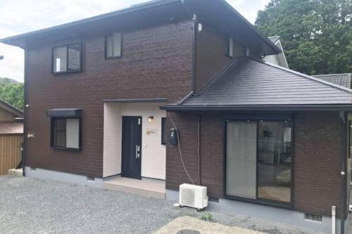 a brown brick house with a black door at Guest House Kiyohime in Tanabe