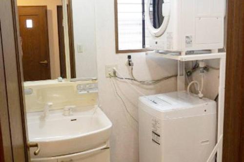 a bathroom with a sink and a toilet and a mirror at Guest House Kiyohime in Tanabe