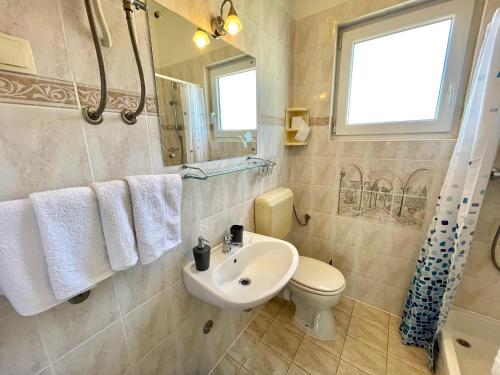 a bathroom with a sink and a toilet and a window at Apartments Mare in Dramalj