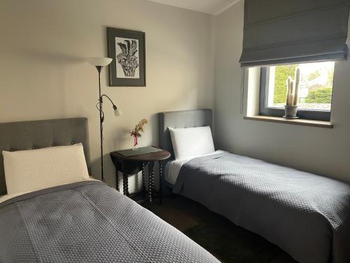 a bedroom with two beds and a table and a window at Pine house in Zujūnai