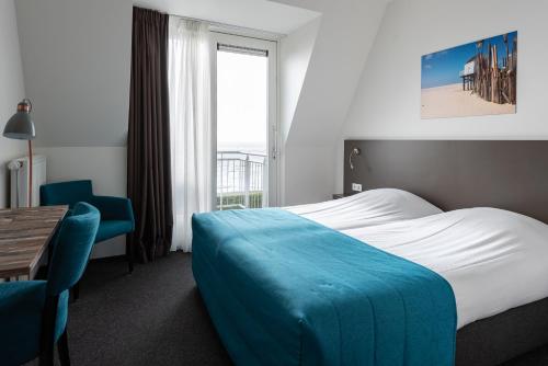 a hotel room with a bed and a table and a window at Hotelletje de Veerman in Oost-Vlieland