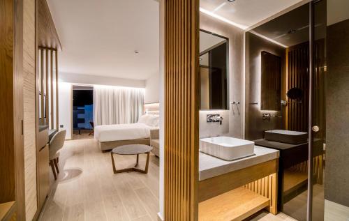 a bathroom with a sink and a bedroom at AKASHA Beach Hotel & Spa in Hersonissos