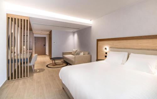a bedroom with a large white bed and a chair at AKASHA Beach Hotel & Spa in Hersonissos