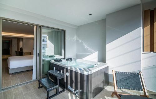 a bathroom with a bath tub and a bedroom at AKASHA Beach Hotel & Spa in Hersonissos