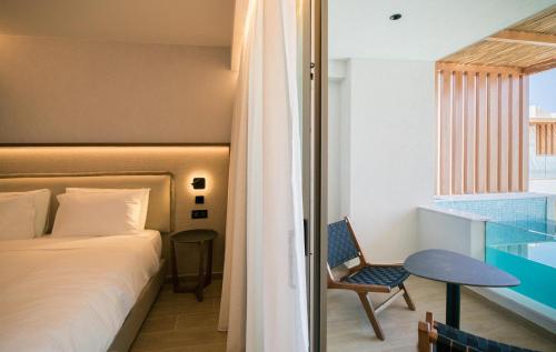 a bedroom with a bed and a table and a window at AKASHA Beach Hotel & Spa in Hersonissos