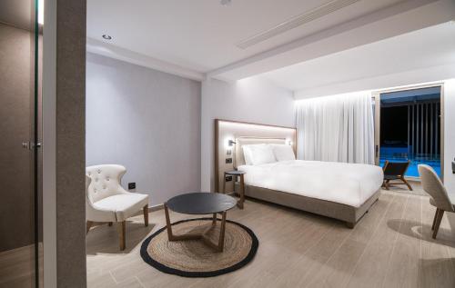 a bedroom with a bed and a table and a chair at AKASHA Beach Hotel & Spa in Hersonissos