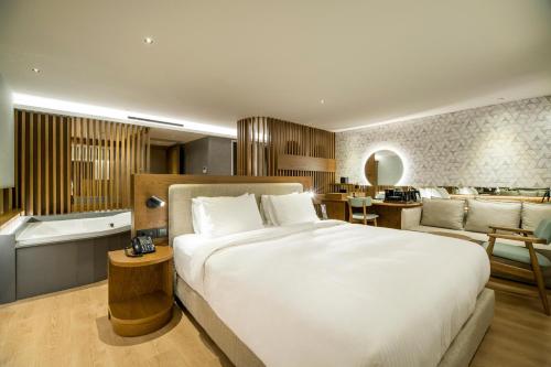 a bedroom with a large bed and a bath tub at AKASHA Beach Hotel & Spa in Hersonissos