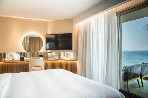 a hotel room with a bed and a view of the ocean at AKASHA Beach Hotel & Spa in Hersonissos