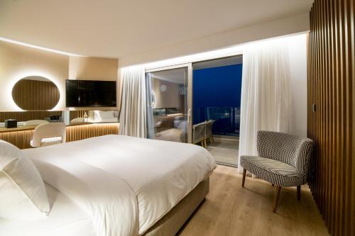 a bedroom with a large white bed and a chair at AKASHA Beach Hotel & Spa in Hersonissos