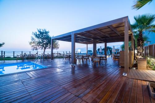 a deck with a table and chairs and a pool at AKASHA Beach Hotel & Spa in Hersonissos