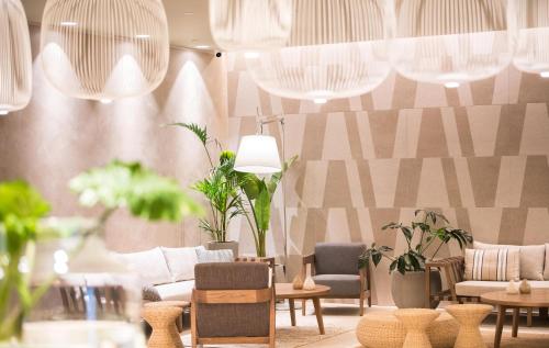 a room with chairs and tables and potted plants at AKASHA Beach Hotel & Spa in Hersonissos