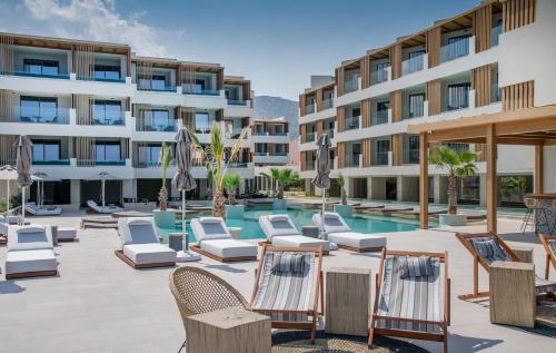 a hotel patio with lounge chairs and a swimming pool at AKASHA Beach Hotel & Spa in Hersonissos