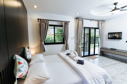 a large white bed in a room with windows at Thai Smile Resort in Rayong